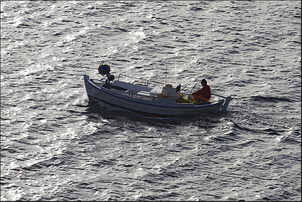 Fisherman returns in the evening in the port of Pollonia on a typical boat of the island