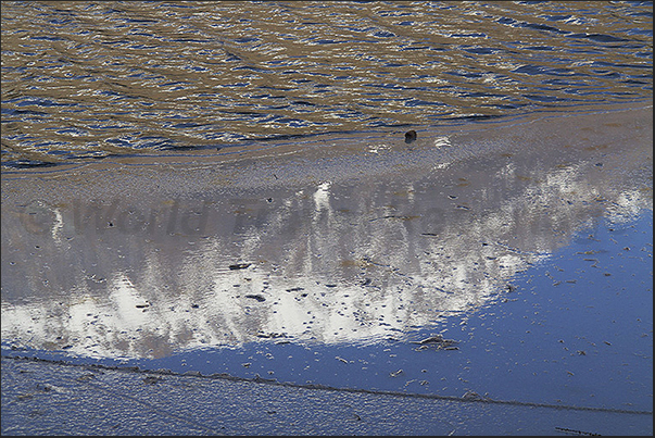 Laux Lake. Reflections of the mountains on the ice on the water surface