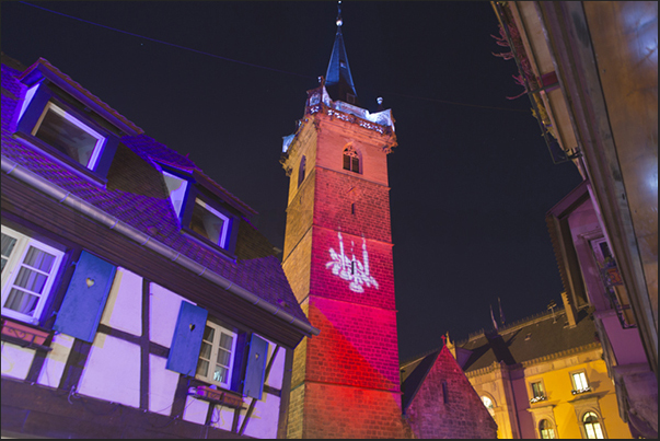 The bell tower in the market square in Obernai illuminated with colored lights during the Christmas season