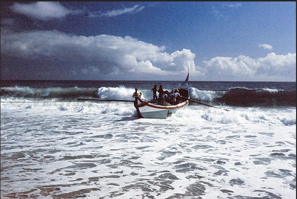 The boat with the fishermen takes advantage of the swell to reach the shore
