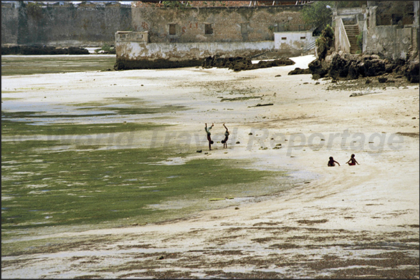 Some children play on the beach at low tide under the ramparts of San Sebastian Fortress.