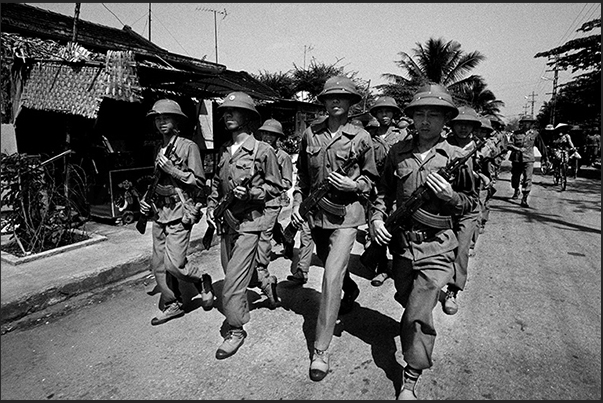 A group of soldiers passing through the streets of a village